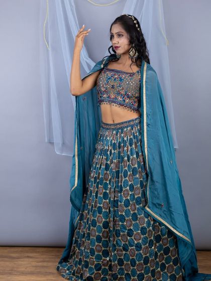 A full-length view of the teal lehenga with a honeycomb-patterned skirt. The cape-style dupatta adds a modern and regal touch.