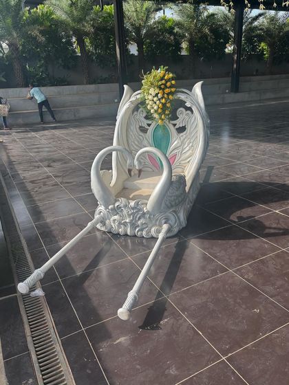 A beautiful white swan-shaped palanquin or doli, available for rent for bridal entries or other ceremonies.