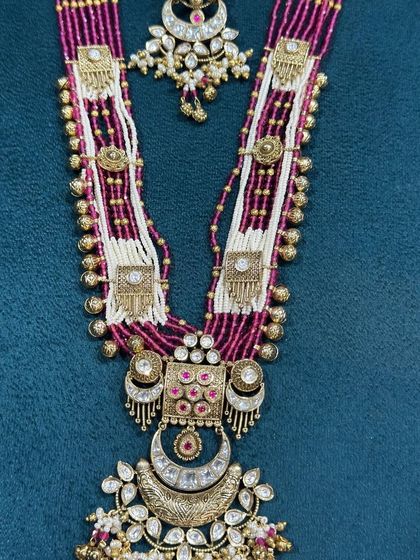 A magnificent temple-style long necklace with a crescent pendant and ruby-colored beads.