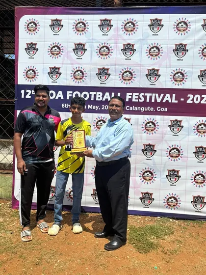 A coach stands proudly with Vihaan as he receives his 'Player of the Team' award.