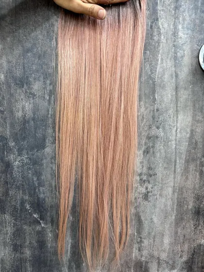 A close-up of a blush pink hair swatch. Testing allows us to perfect the tone, whether we want it more peachy, rosy, or neutral.