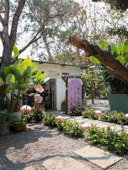 A whimsical garden-themed birthday party at Backyard. The pathway is lined with decorative mushrooms, leading to the beautifully decorated entrance of the cottage.