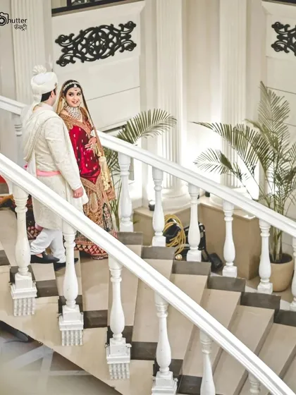 An elegant portrait of the couple on a grand white staircase. We utilize the architecture of your venue to create stunning, magazine-worthy wedding photos.