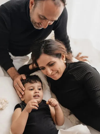 A quiet, intimate moment during a family session. The parents look down lovingly at their son, creating a feeling of warmth and protection.