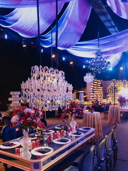 A stunning view of the reception, with a ceiling of draped fabric and crystal chandeliers over mirrored tables, creating a dreamlike and opulent atmosphere.