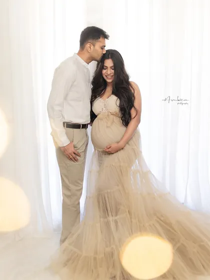 A tender moment between the couple, with soft bokeh lights adding a touch of magic. This portrait is filled with love, warmth, and anticipation.