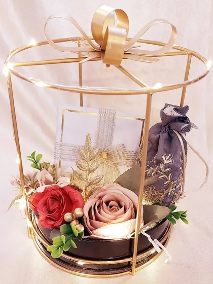 Make any occasion extraordinary with our elegant hampers. This metal cage hamper is lit with fairy lights and contains beautifully wrapped gifts, creating a magical unboxing experience.
