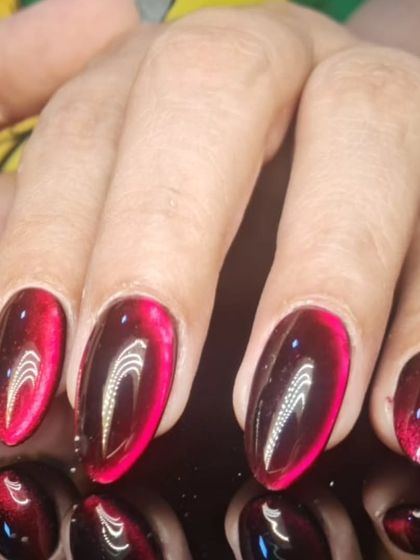 A close-up of the red and black cat-eye nails, showing the depth and intensity of the magnetic shimmer.