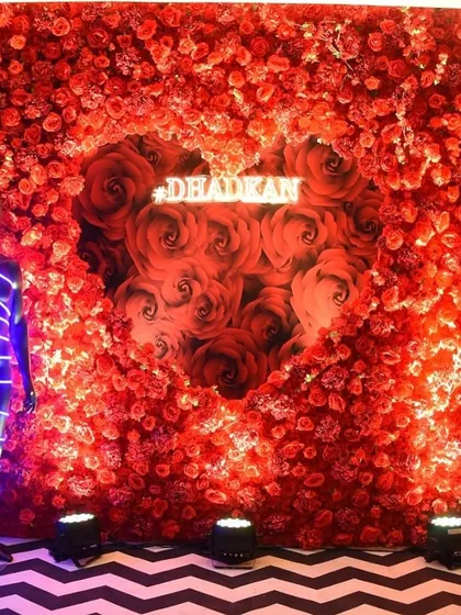 A bold and romantic photo wall made entirely of red roses, with a heart-shaped cutout and a custom neon sign, creating a dramatic and passionate backdrop.
