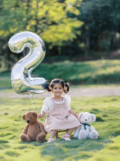 A little girl with a "2" balloon and her teddy bears. A classic setup for a second birthday shoot.