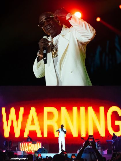 A split-screen view of Akon's concert, showing him performing on a grand scale with "WARNING" displayed on the screen behind him.
