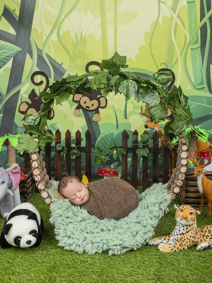 This little one is sleeping peacefully in a hammock, surrounded by friendly jungle animals in this adorable newborn jungle theme setup.