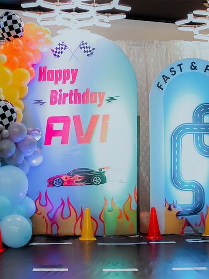 The complete Hot Wheels "Fast & Five" backdrop, featuring a custom-printed race track, flame details, and checkered flag balloons. The light-up number '5' adds a dynamic touch to the setup.