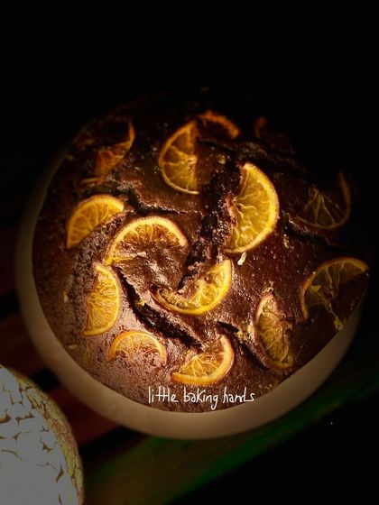 The dramatic lighting highlights the texture and rich colour of this chocolate and orange whole wheat cake.
