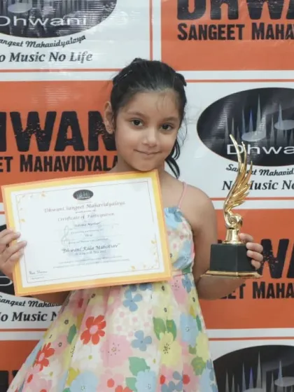 A young student proudly holds her certificate and trophy.