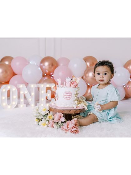 A full setup for a first birthday cake smash, with balloons, flowers, and a "ONE" sign. I bring everything needed to create a beautiful scene at your home.
