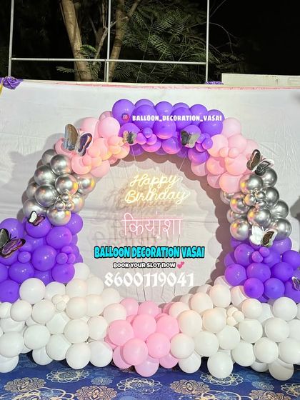 A beautiful first birthday ring decoration in purple, pink, and white. The setup is accented with silver chrome balloons, butterfly stickers, and a number '1' foil balloon.