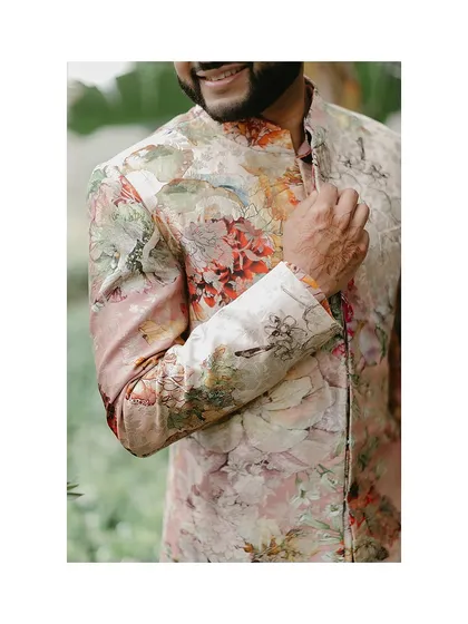 A close-up on the details of the groom's floral print sherwani. We believe that the beauty of an outfit is often in the fine details of its craftsmanship.