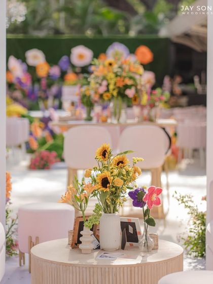 A table centerpiece featuring a bright bouquet of sunflowers, complemented by whimsical crocheted flowers and personalized books.