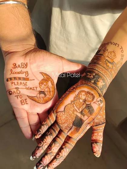 A beautiful shot of the couple's hands together. The mom to be has a portrait of her and her partner, while the dad to be has a "Baby loading" message on his palm.