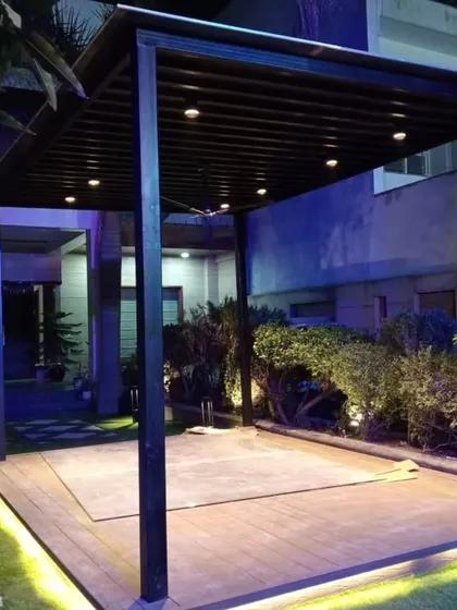 The Dwarka pergola at night, with spotlights and under-deck lighting creating a dramatic and elegant effect.