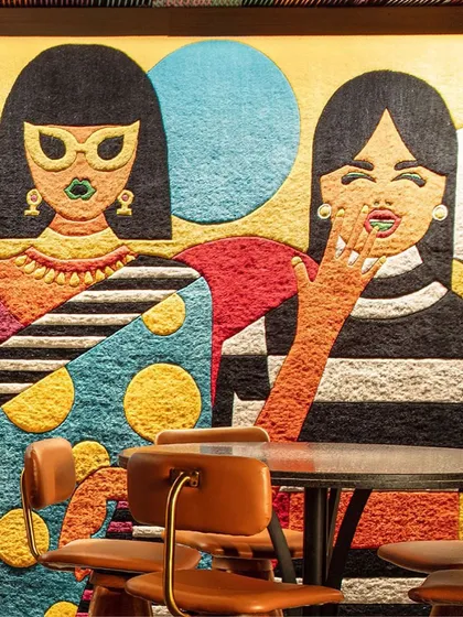 A close-up of the bespoke wall carpet at Khi Khi, a custom creation by The Carpet Cellar. The design features whimsical, giggling motifs and a curated explosion of colors that perfectly captures the bar's playful spirit.