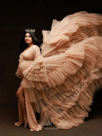 A queen taking flight. The dramatic sweep of this ruffled nude gown creates a sense of power and movement, celebrating the majestic journey of motherhood.