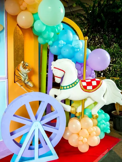 A carousel horse and decorative wheel prop add to the whimsical carnival atmosphere.
