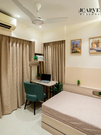 This bedroom features a compact study corner cleverly integrated next to the bed. The design includes a sleek desk, an ergonomic chair, and overhead storage, creating a functional workspace without cluttering the room.