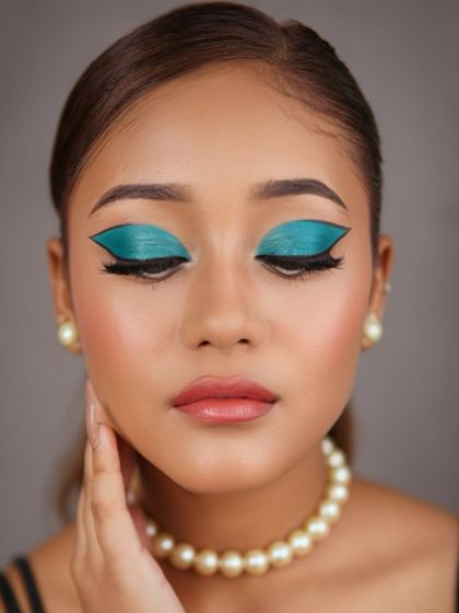 A fusion makeup look with a bold, graphic teal winged eyeshadow. Paired with a simple pearl necklace, this look is a perfect blend of modern art and classic elegance.