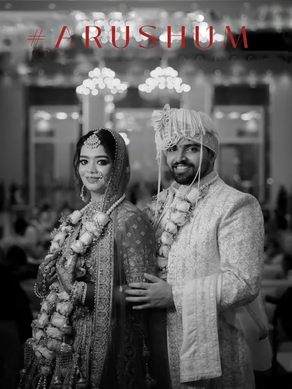 A classic black and white portrait of the couple after their wedding ceremony, standing in a grand, well-lit hall.