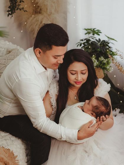 A warm family portrait capturing the new parents admiring their swaddled baby.