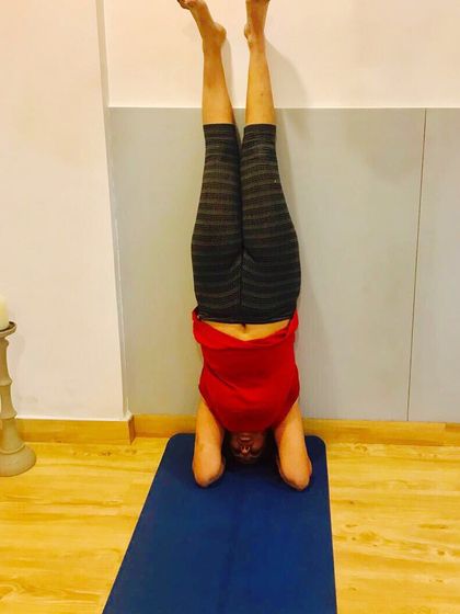 Every student's journey is unique. This practitioner is finding her balance and strength in a supported headstand, a key milestone in many yoga journeys that I am happy to guide.