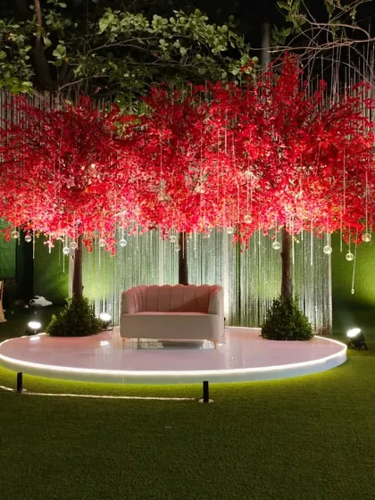 A whimsical and romantic photo point for a reception. I used two vibrant red cherry blossom trees to frame a simple love seat, all set on an illuminated circular stage.