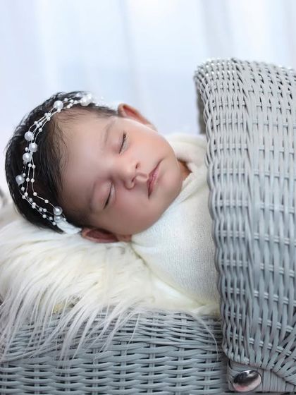 A detailed close-up of the newborn in the pram, showing her pearl-adorned headband and serene expression as she sleeps.