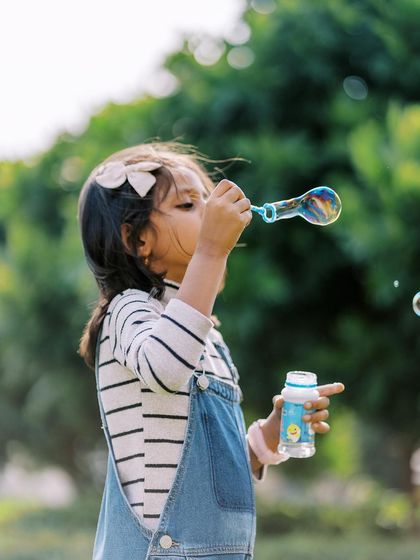 A little girl blowing a big bubble. A simple pleasure that creates a magical photo.