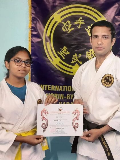 A student receives her well earned certificate in front of the official banner of our organization. This signifies her connection to a worldwide community dedicated to traditional Okinawan martial arts.