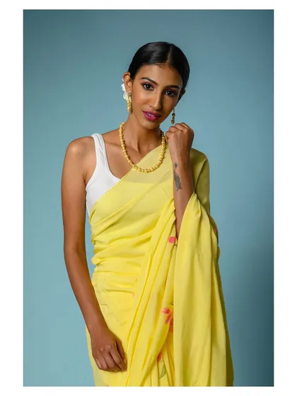 A close-up shot focusing on the details of the yellow saree and the complementary necklace.