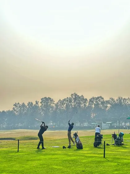 Two golfers in perfect sync, their swings captured mid-motion against a hazy sky.