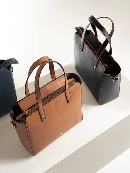 A clean, minimalist shot of two tote bags on a white, tiered surface. This is a perfect setup for an e-commerce catalogue, showing the product clearly from a flattering angle.