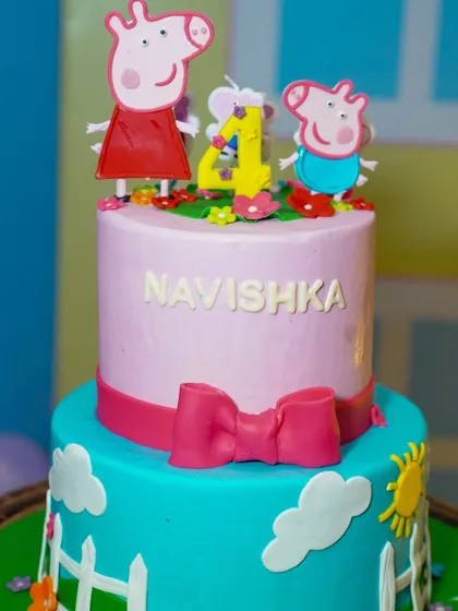 A close-up of the adorable two-tiered Peppa Pig cake, complete with character toppers and a cheerful design.