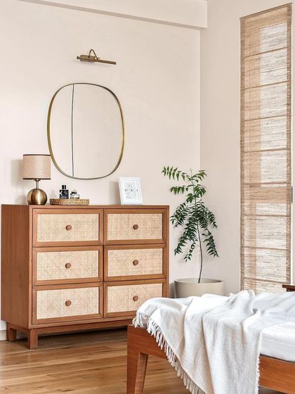This image from a magazine feature shows the master bedroom, where a rattan-front chest of drawers and banana fiber blinds create a cohesive, earthy look.