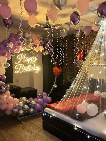 A beautiful bedroom setup with a pastel balloon arch, a neon sign, and a bed canopy with fairy lights.