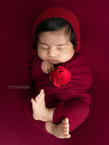 A newborn wrapped in a deep red swaddle, holding a single red rose. This powerful and loving image is perfect for celebrating your little valentine.