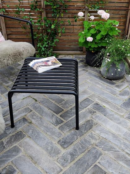A herringbone-patterned brick floor provides a stylish and durable surface for this patio seating area. We combine classic materials with modern furniture to create a timeless look.