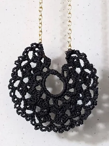 The black crochet lace pendant is a versatile piece that adds a touch of bohemian elegance to any outfit. It's a perfect example of our detailed thread jewellery.