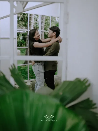 A romantic embrace framed by a window, creating a sense of intimacy and a beautiful, layered composition.