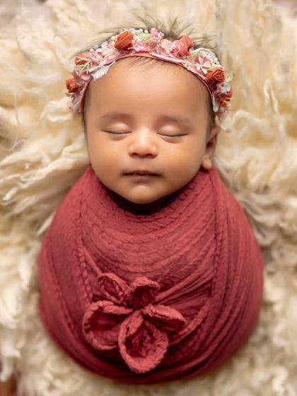 A smiling newborn surrounded by a bed of beautiful flowers. This shot is full of color, life, and happiness.