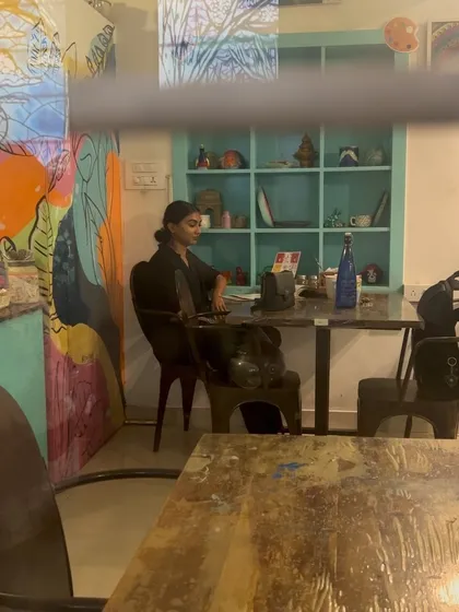 A quiet corner of the cafe, where a guest is focused on her work. The colorful murals and artistic decor create an environment that is both stimulating and peaceful.
