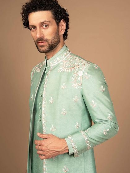 A closer look at the mint green bandhgala, highlighting the intricate floral embroidery. This piece is designed for a man who appreciates sophisticated style and celebratory color.